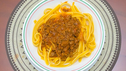 Cenit view on a dish of pasta with bolognese sauce on top. Horizontal image.