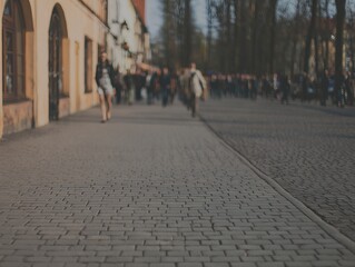 Fototapeta premium People Walk Along a Street as the Sun Sets in a Busy Part of the City