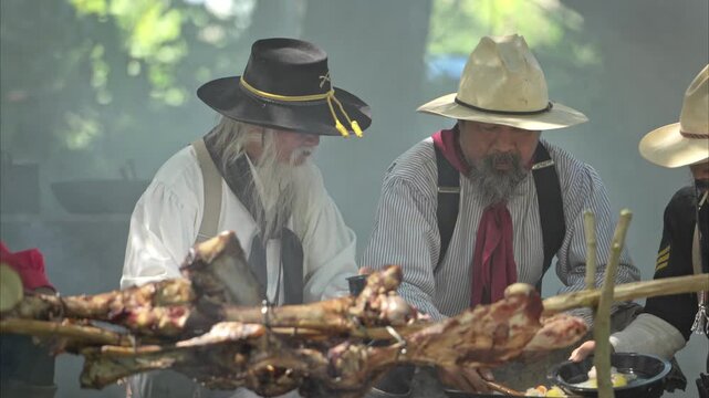 Group of cowboys preparing food at a campfire, roasting meat together in a warm and rustic outdoor setting