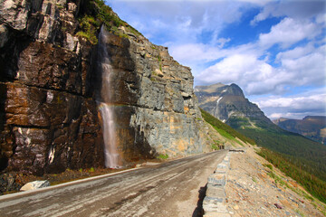 Waterfall flows down from the mountains onto the Going To The Sun Road in Glacier National Park