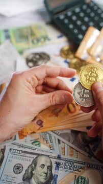 Hands shows silver and golden BTC bitcoin against the dollars and euros