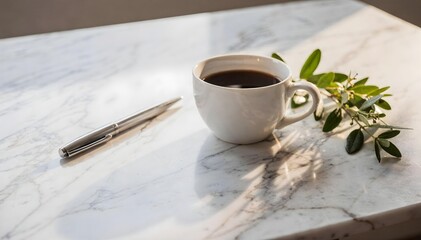 Cup of black coffee on a white marble table with a silver pen and green leafy branch in bright sunlight.