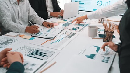 A diverse group of business professionals engaged in a collaborative meeting, discussing charts and documents while utilizing modern technology in a sleek office setting. SACTR - Powered by Adobe