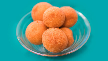 Close up of a bowl with six fritters inside on light green background. Horizontal image.