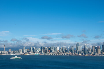 Naklejka premium Seattle skyline across Elliot Bay on sunny day with ferry in bay