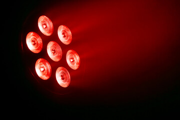 High-intensity red LED spotlight projecting a powerful beam into darkness. Dramatic stage lighting...