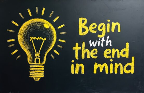 Black chalkboard with bright yellow glowing light bulb sketch and quote Begin with end in mind written in chalk. This image suggests ideas creativity and wisdom. Good visual for planning and strategy.