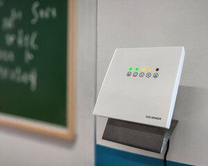 CO2 monitor warning to ventilate classroom. Carbon dioxide monitor with green yellow indicator lights signaling rising CO2 levels and poor indoor air quality. Preventive health measures
