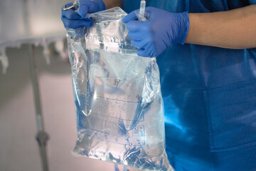 Healthcare professional preparing intravenous fluid bag for infusion
