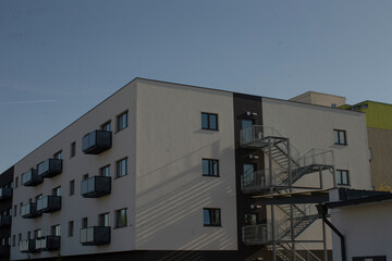 row of glass balconies linear shadows, repeating terrace modules along crisp facade, reflective panels catching warm light, study