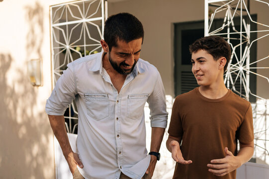 Father and teenage son walk side by side in a quiet residential area, having an open conversation about life, emotions, and wellbeing, representing trust, guidance, and mental health support