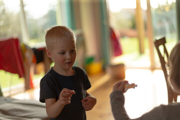 Fototapeta premium White boy reaching into woven toy basket on couch, leaning across cushions to find favorite figure, eager movement, bright