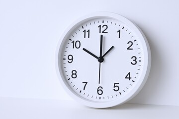Minimalist White Wall Clock Displaying Ten O'Clock, Against a Plain Background