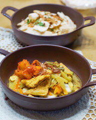 Authentic Indonesian traditional dish served in ceramic bowls with rice cake, vegetables, tofu, curry sauce and fried shallots. Asian comfort food concept