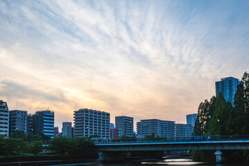 夕焼けの空と川沿いのマンション群、黄昏時の都市風景