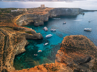 Epic turquoise lagoon hidden sanctuary.  Cinematic aerial view of  historic watchtower overlooking  crystal clear bay in  Comino island, Malta.  © Yar