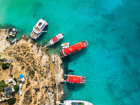 High angle aerial view of Blue Lagoon in Comino island, turquoise crystal clear water and luxury yachts on the coast of Malta, 4K drone
