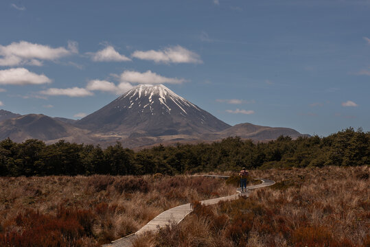 Distant view of the volcanic Mount Ngauruhoe in the Tongariro National Park, New Zealand. Female hiker on the track in the foreground.