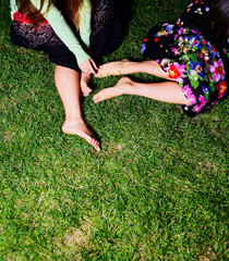 Relaxation: Two Women Sitting Barefoot on Grass Wearing Colourful Dresses in Outside Setting During Daytime Copyspace