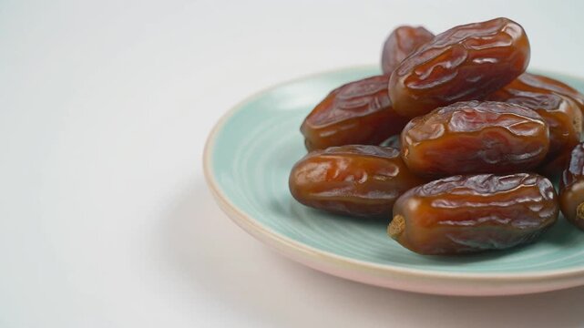 Delicious dates on a pastel ceramic plate with soft lighting and a clean white background. High-quality food footage.