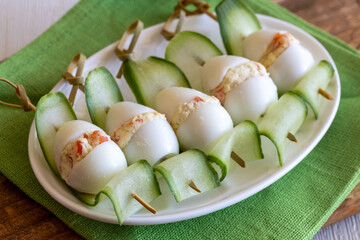Skewers from stuffed quail eggs with salmon and cucumber slices. Buffet dish, top view, close up. Easter meal, food for kids birthday party