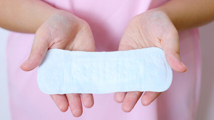 Woman carefully examining sanitary pad, demonstrating personal hygiene awareness, supporting feminine health management and menstrual comfort with essential personal care product