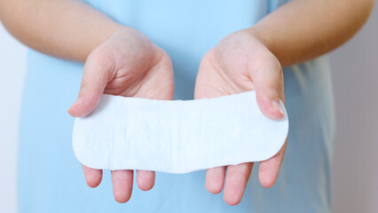 Female healthcare worker in light blue scrubs, demonstrating sanitary pad, emphasizing feminine hygiene, menstrual wellness, and women's health care