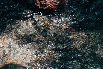 Sunlit Clear Stream Water Flowing Over Stones