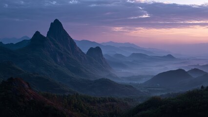 Fototapeta premium Jagged peaks rise from misty valleys under a soft purple and pink sunrise sky