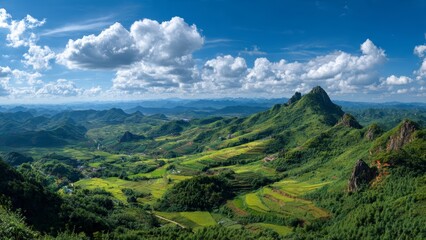 Obraz premium Vast green mountain landscape with terraced fields rolling hills and a bright blue sky