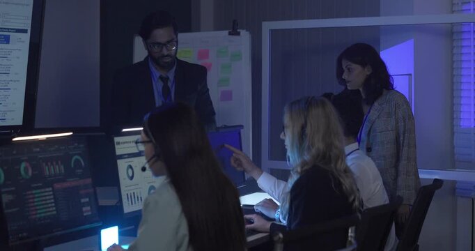A focused team wearing headsets monitors live analytics dashboards and collaborates in modern control room. Highlighting customer support, data driven decision making, coordinated incident response.
