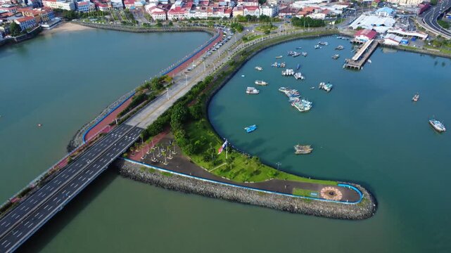 Aerial view of  Panama's Old town, a coastal road and harbor filled with boats and a pier with the Panamanian flag waving near ''Casco Viejo''
