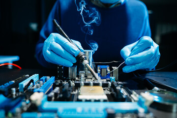 Closeup of expert soldering a green PCB board using precision tools. Ideal for electronics, circuit repair, engineering, tech