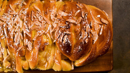 Sweet braided brioche bread loaf with glazed topping and slivered almonds dusted with powdered...