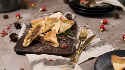 Golden brown pastries filled with spiced fruit compote rest on a wooden board. The scene features...