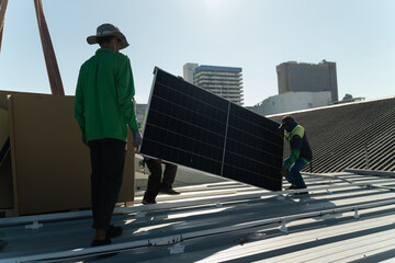 Workers install solar panels on a rooftop at a construction site in a city on a sunny day