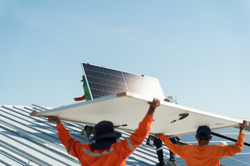 Workers install solar panels on a roof under a clear blue sky in a construction site during daytime hours