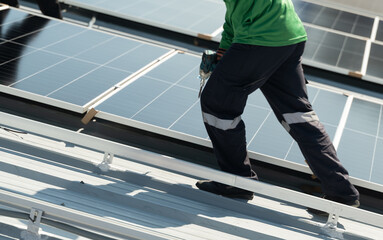 Workers install solar panels on a commercial roof during daylight in a busy urban area