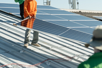 Workers install solar panels on a roof during bright daylight hours in an effort to harness renewable energy