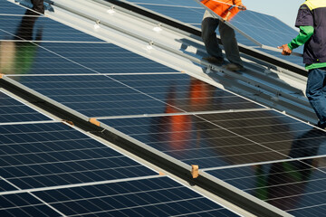 Workers install solar panels on a rooftop during clear weather in a busy urban area in the afternoon