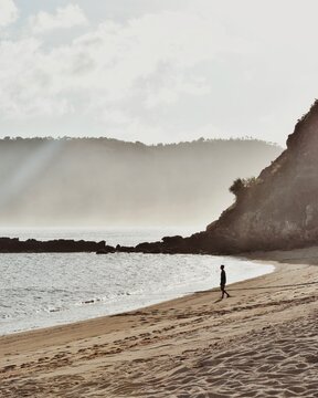 A person is walking on the beach, heading for a boat in Lombok