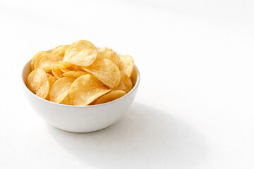 A white bowl filled with crispy golden potato chips on a clean white background with a subtle shadow.