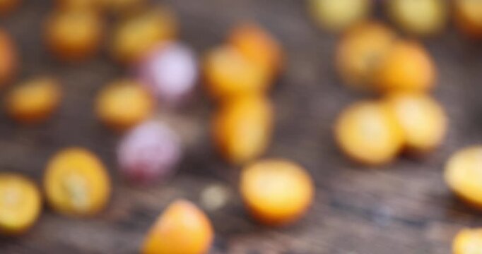 ripe orange kumquat cut in half on a wooden table, a group of sliced kumquat fruits on a wooden table and board