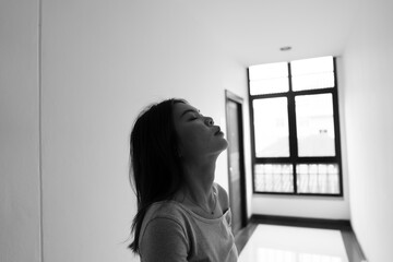 A lonely young woman sits on the floor in a narrow hallway, clutching her head in despair, expressing sadness, stress, and emotional conflict in the quiet, simple interior of the building. The image i