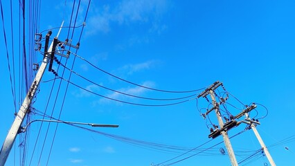 Electric Lines in the Sky: A view of high-voltage power lines reaching upwards, starkly contrasting against a vast, clear blue sky.