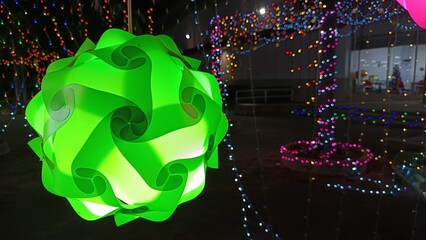 Illuminated Geometric Sculpture: A vibrant, geometric light fixture stands out with its intricate design and captivating glow, creating a stunning visual display against a backdrop of festive lights.