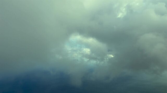 An immersive pilot&rsquo;s perspective taken from the cockpit of a jet airplane while breaking throiugh wispy clouds bathed by the warm sunset light, over a flat landscape.
