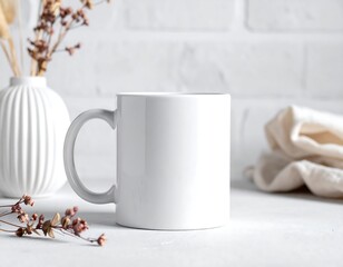 White ceramic mug sits center, vase with dried flowers, draped cloth, white brick backdrop in soft focus