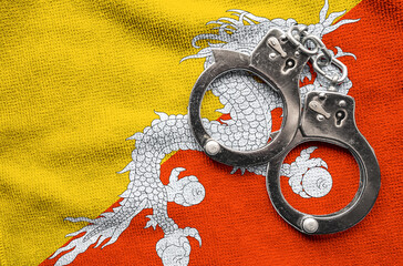 Flag of Bhutan and police handcuffs. Crime and offenses in country Concept
