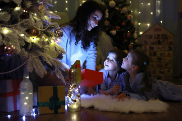 Fototapeta premium New Years Eve. The house is decorated for the holiday. Smartly dressed Christmas tree with a garland and a family with gifts and a surprise.